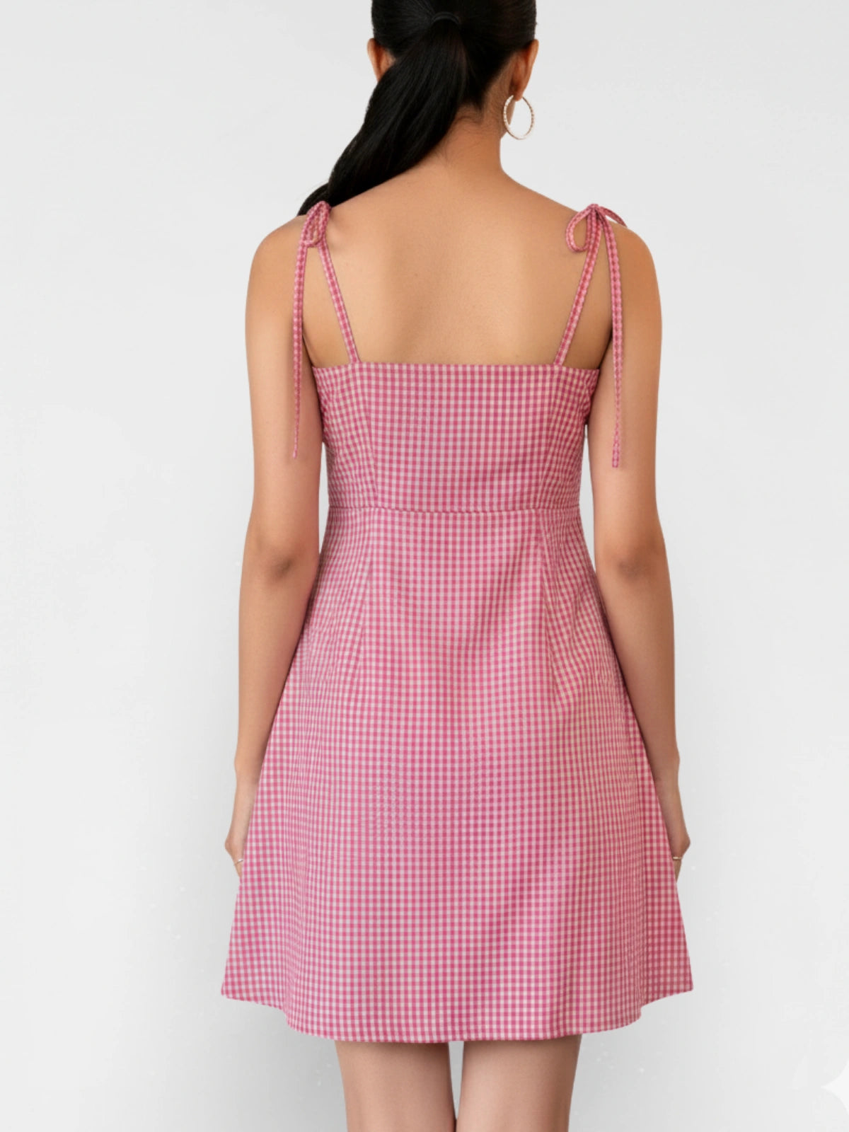 Pink checkered dress worn by a person on a white background