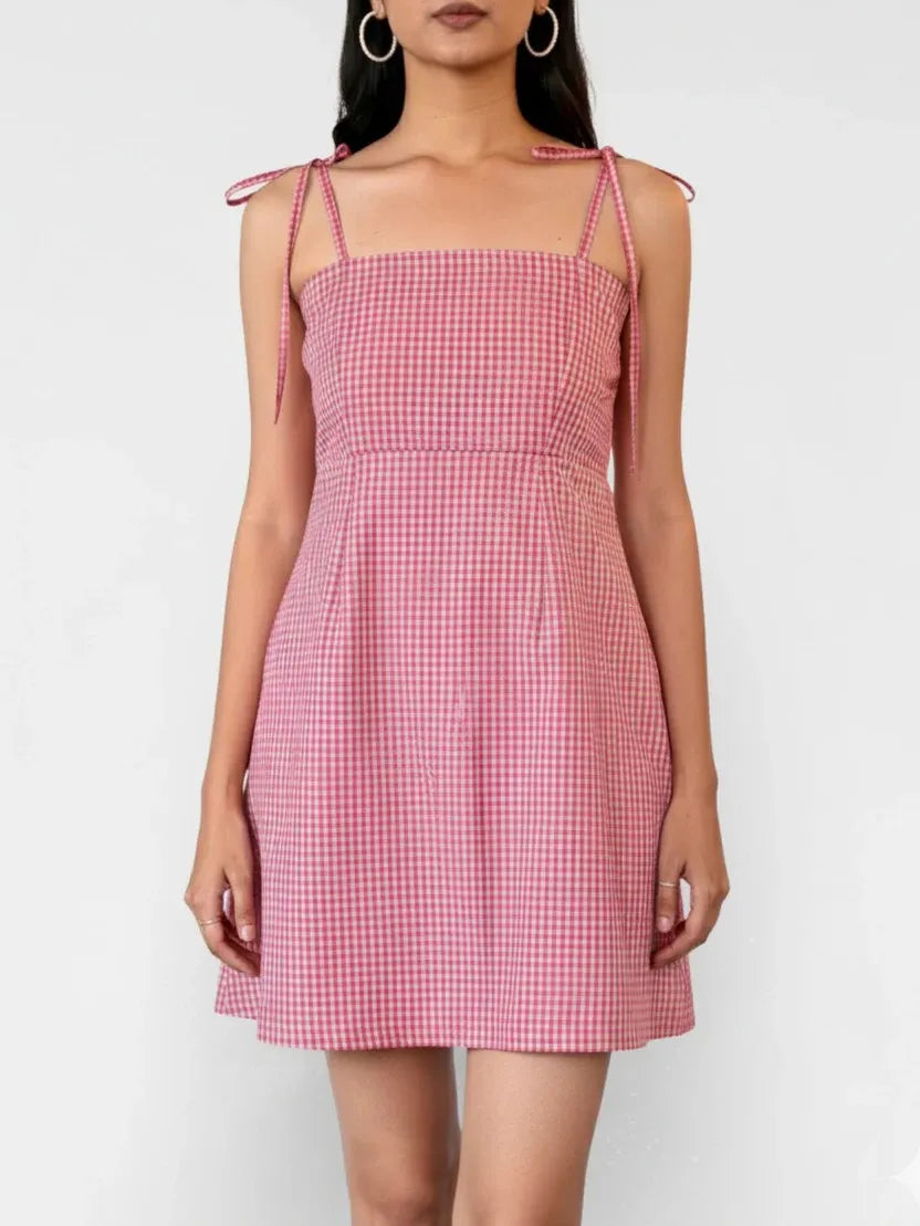 Woman wearing a pink checkered dress against a white background