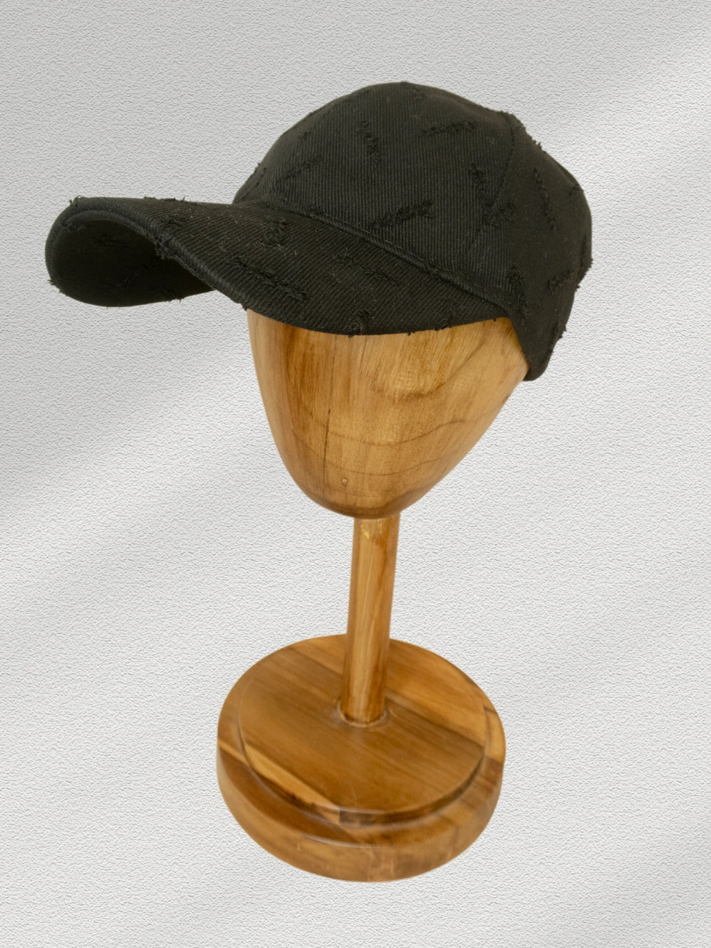 Black cap on a wooden mannequin head against a light gray background
