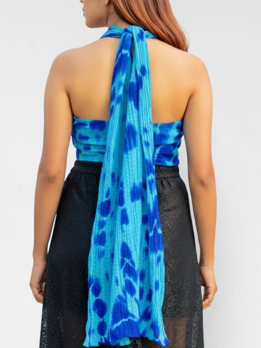 Woman wearing a blue patterned halter top with a plain background