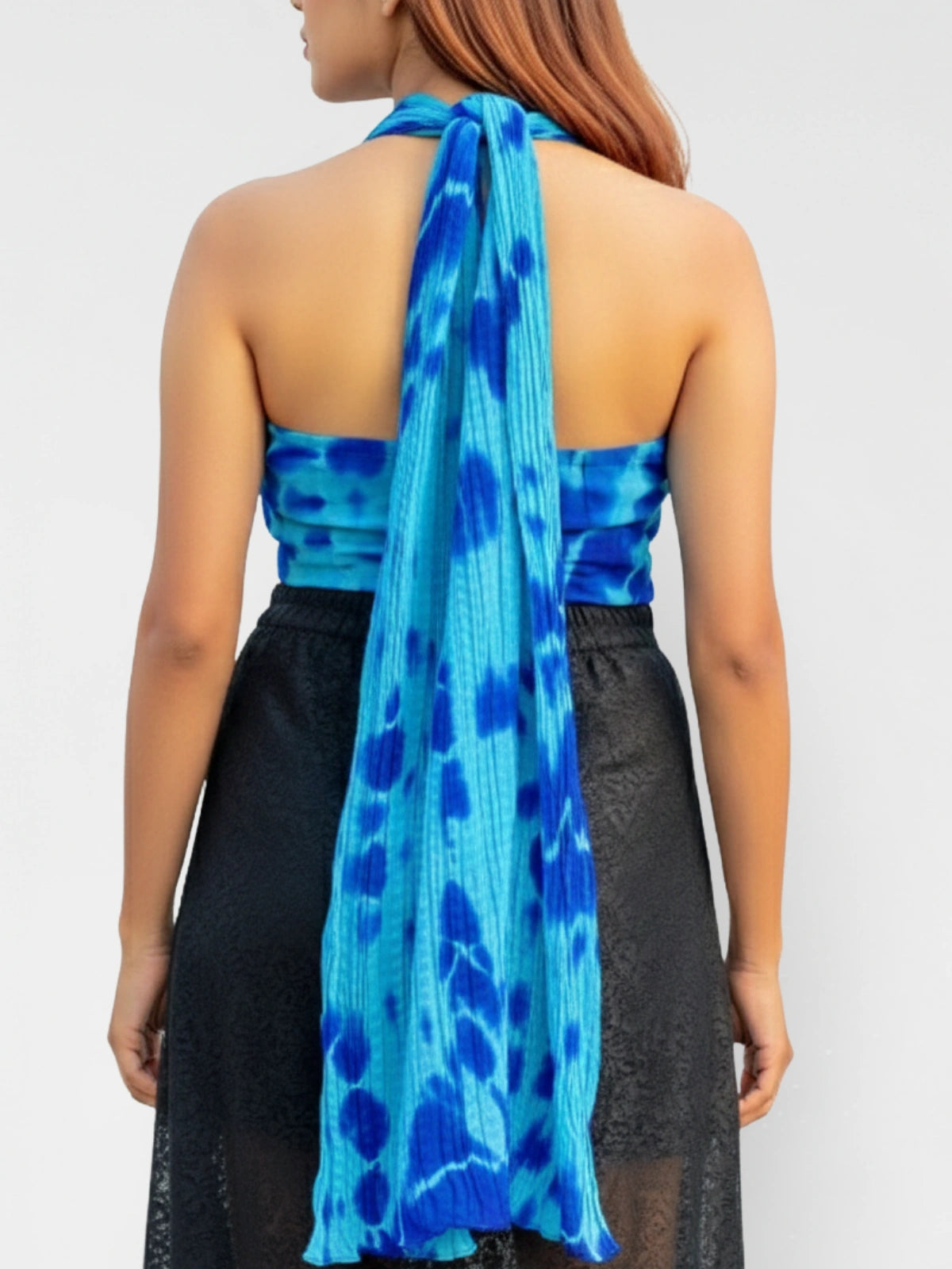 Woman wearing a blue patterned halter top with a plain background