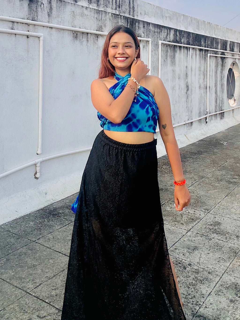 Woman wearing a blue top and black skirt on a rooftop.