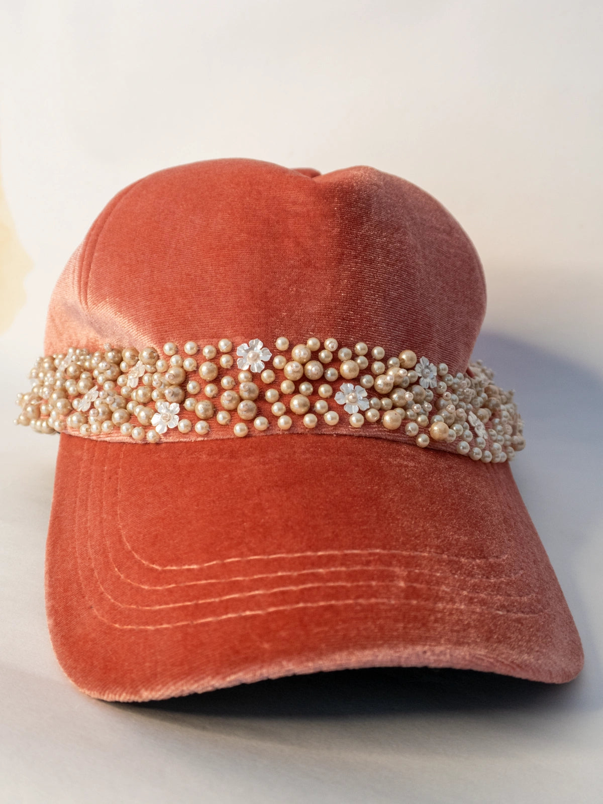 Coral velvet cap with pearl embellishments on a light background