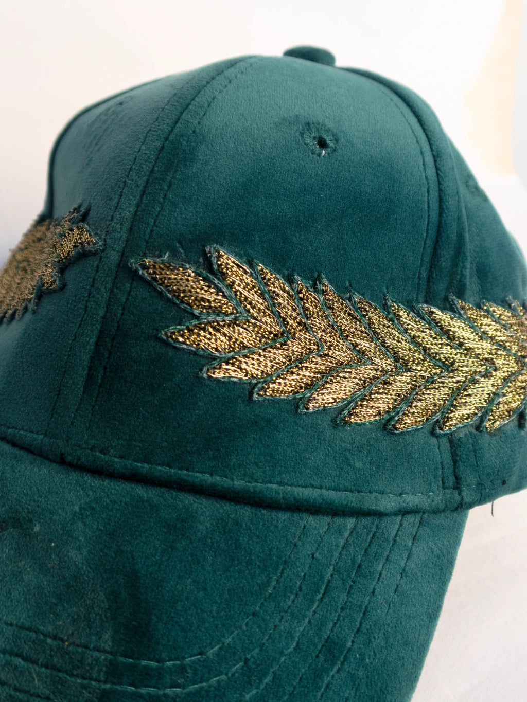 Green cap with embroidered leaf design on a white background