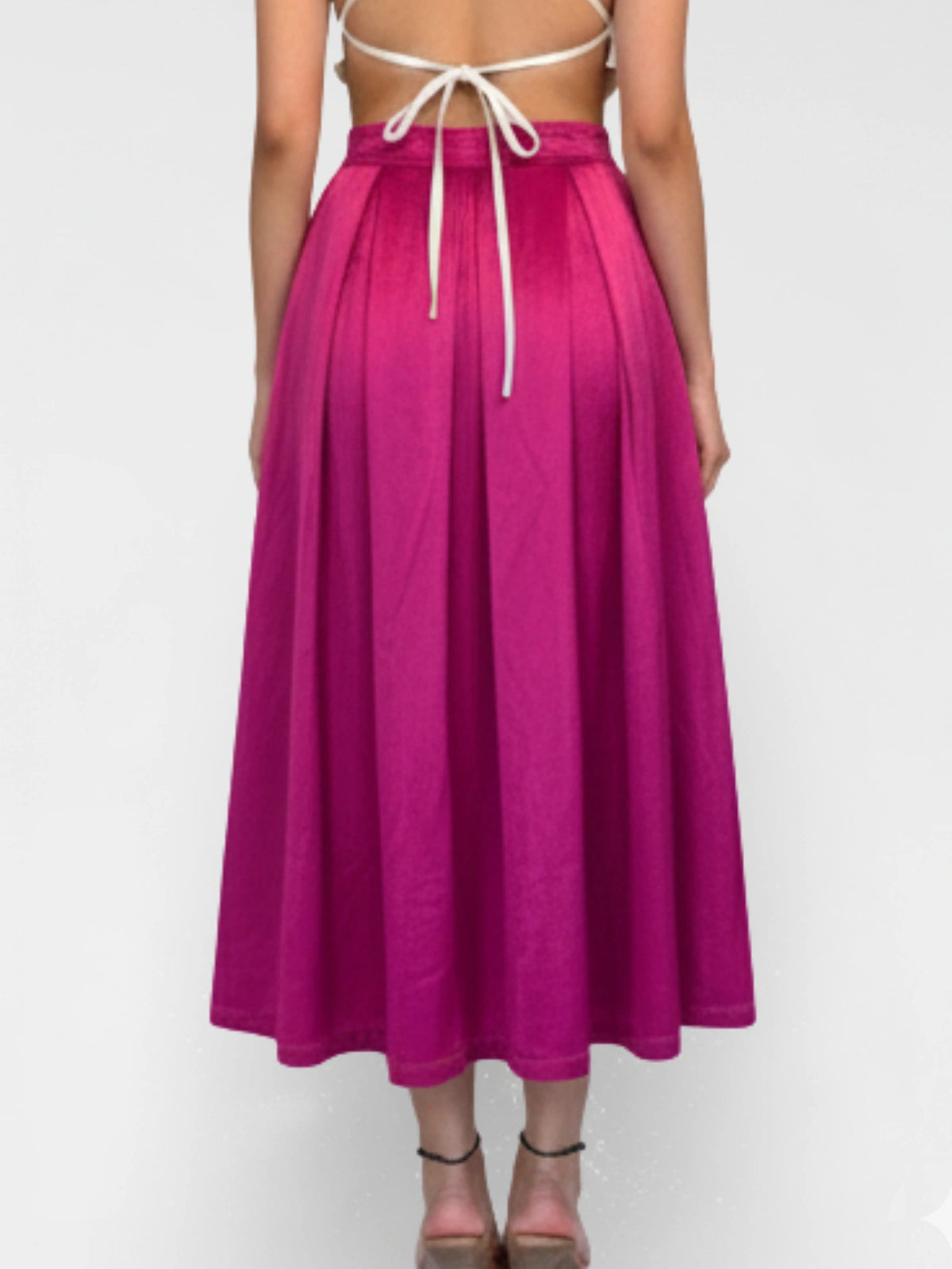 Person wearing a bright pink skirt with a white top on a light gray background