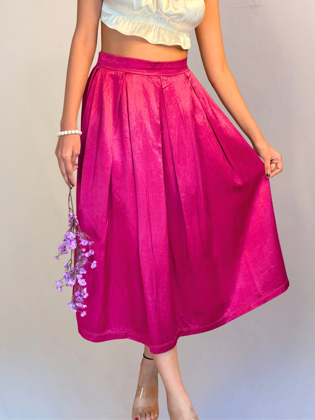 Person wearing a bright pink skirt with a plain background
