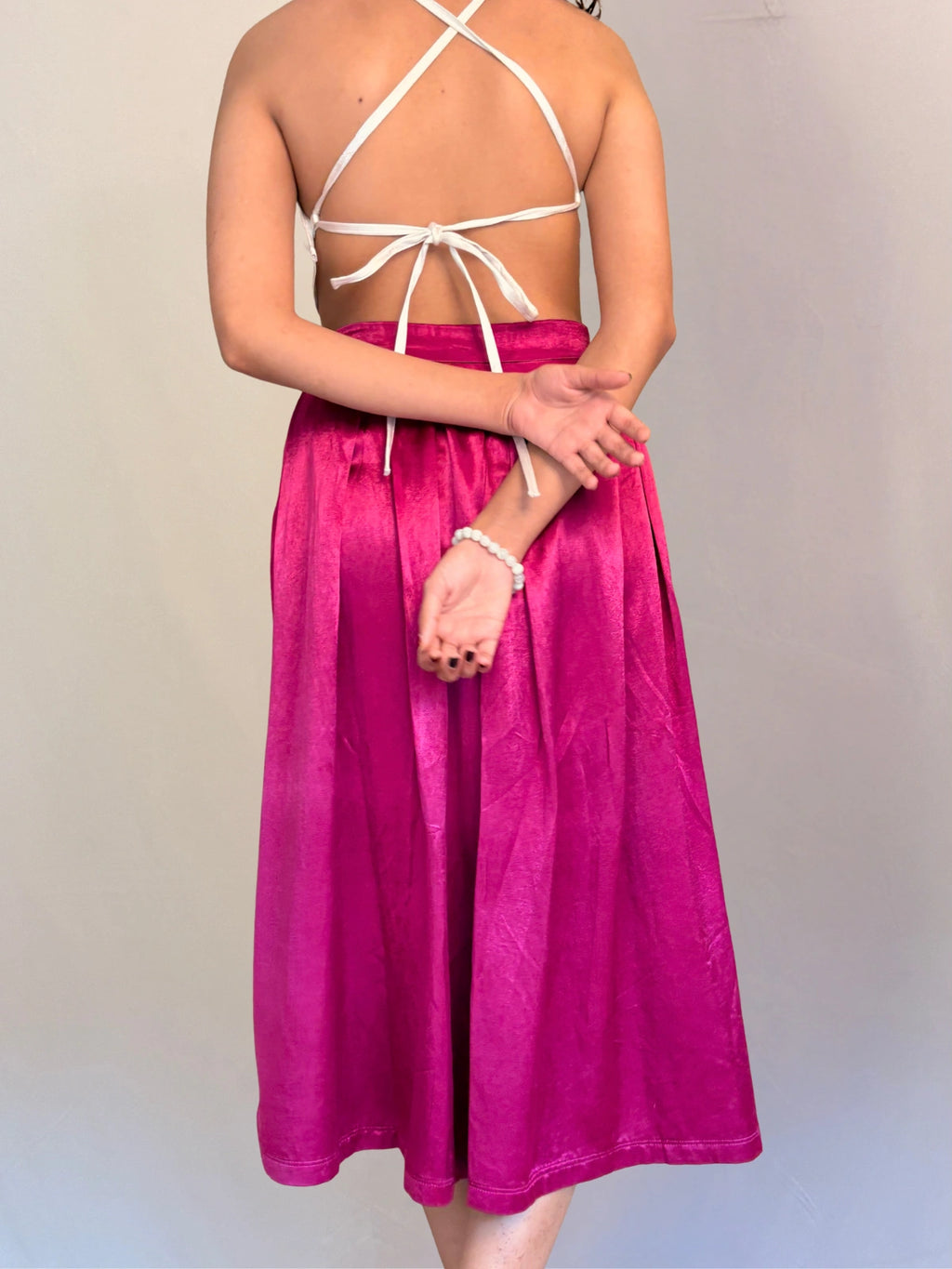 Person wearing a pink skirt with a white top against a plain background