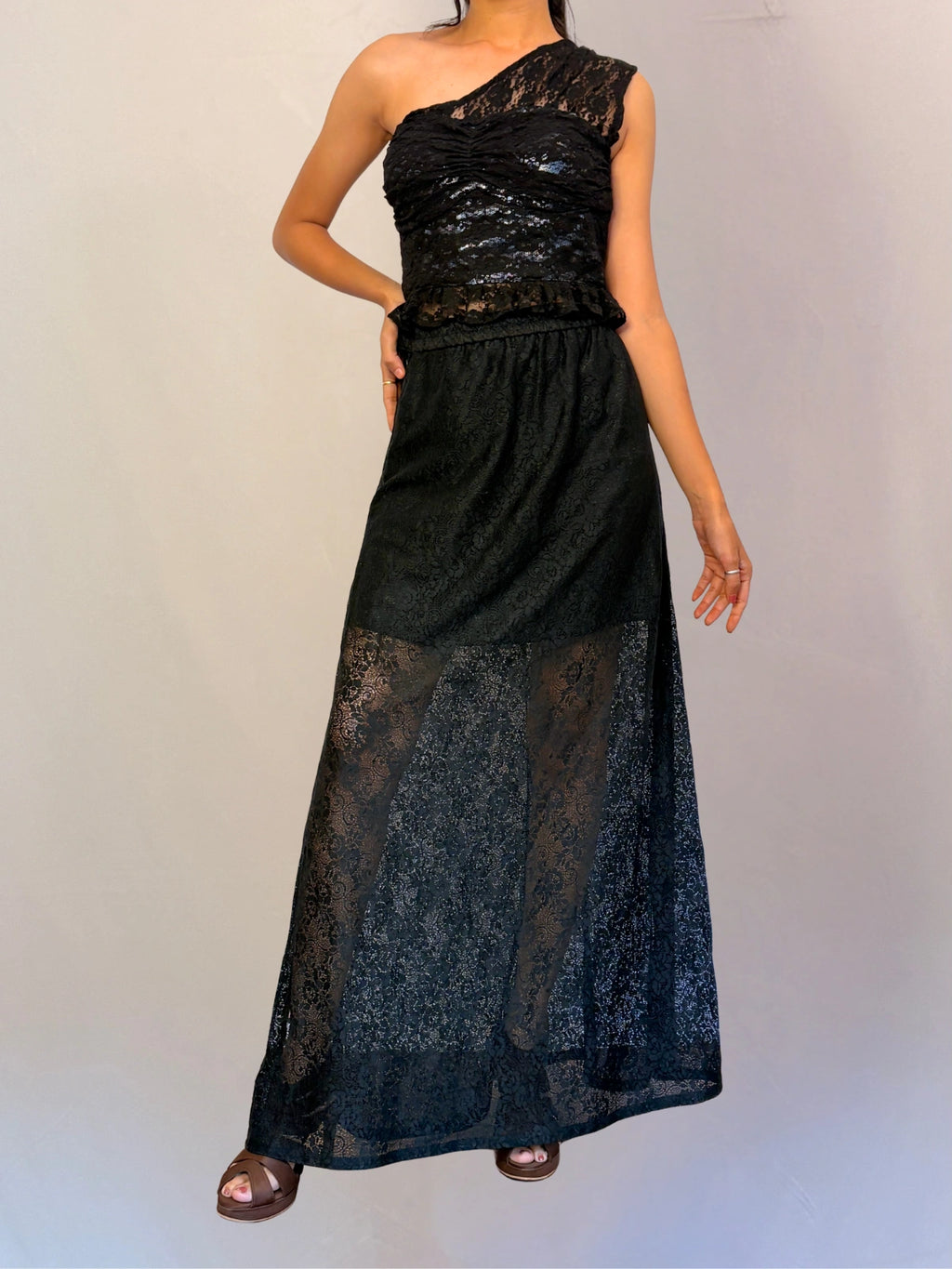 Black lace one-shoulder dress on a plain background