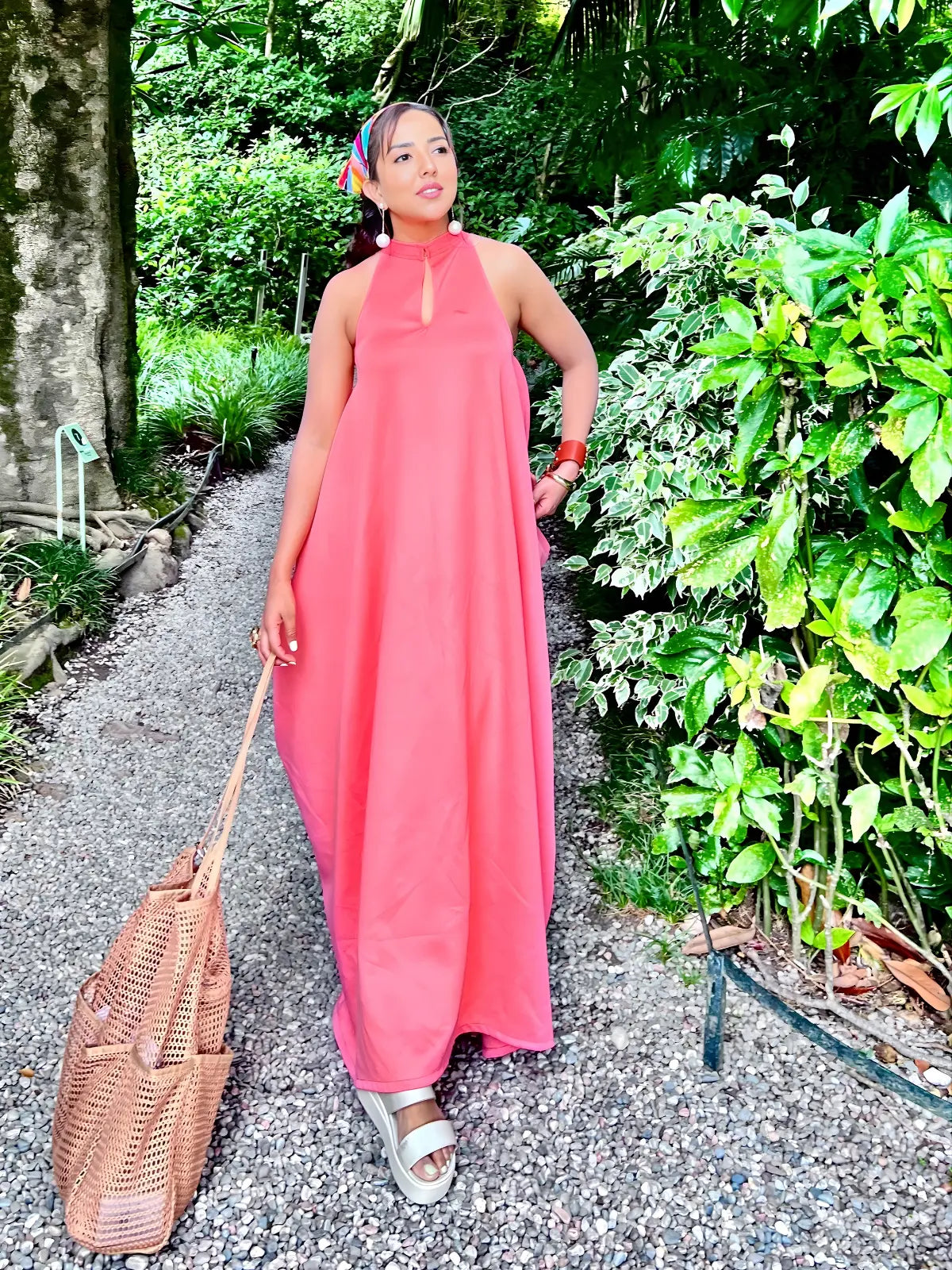 Woman in a pink dress walking on a path surrounded by greenery