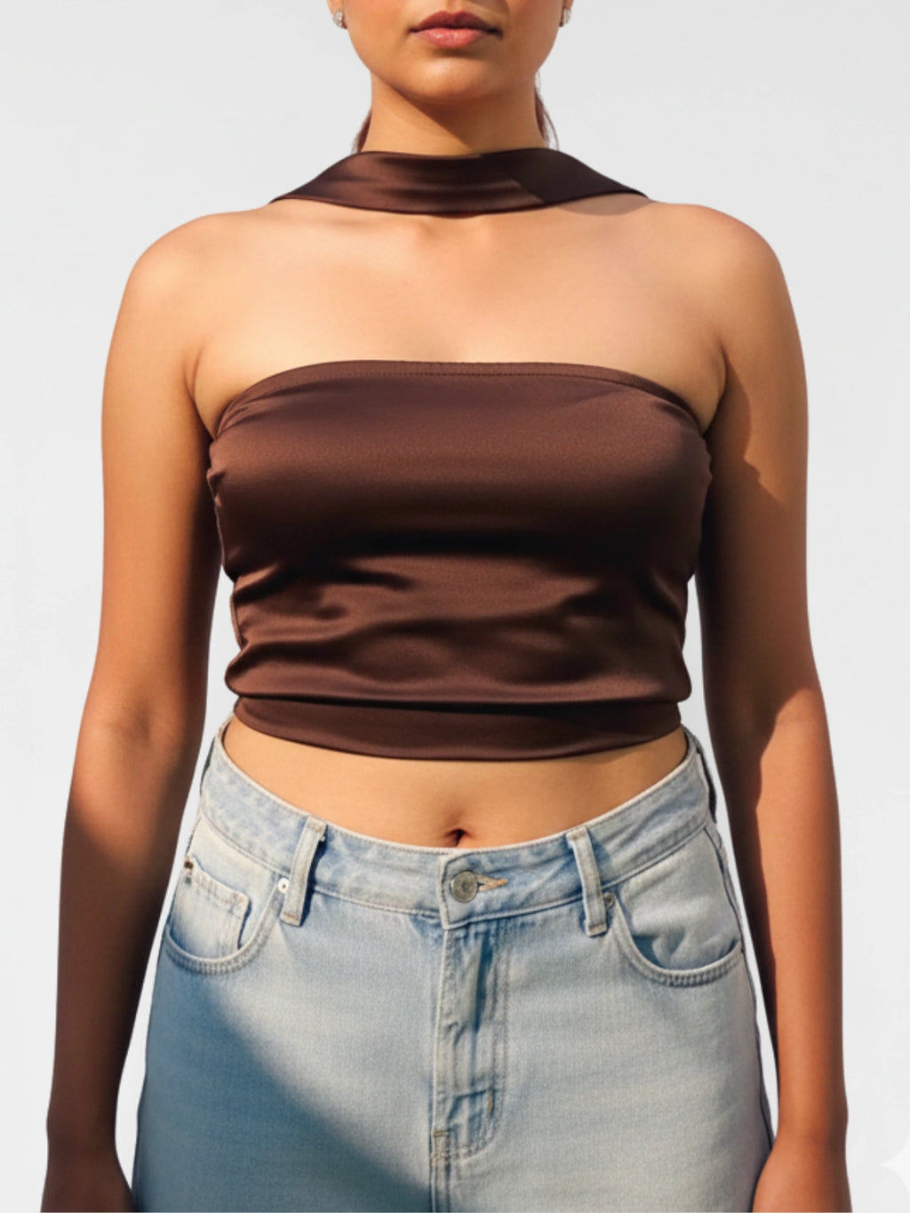 Woman wearing a brown tube top and light blue jeans against a plain background
