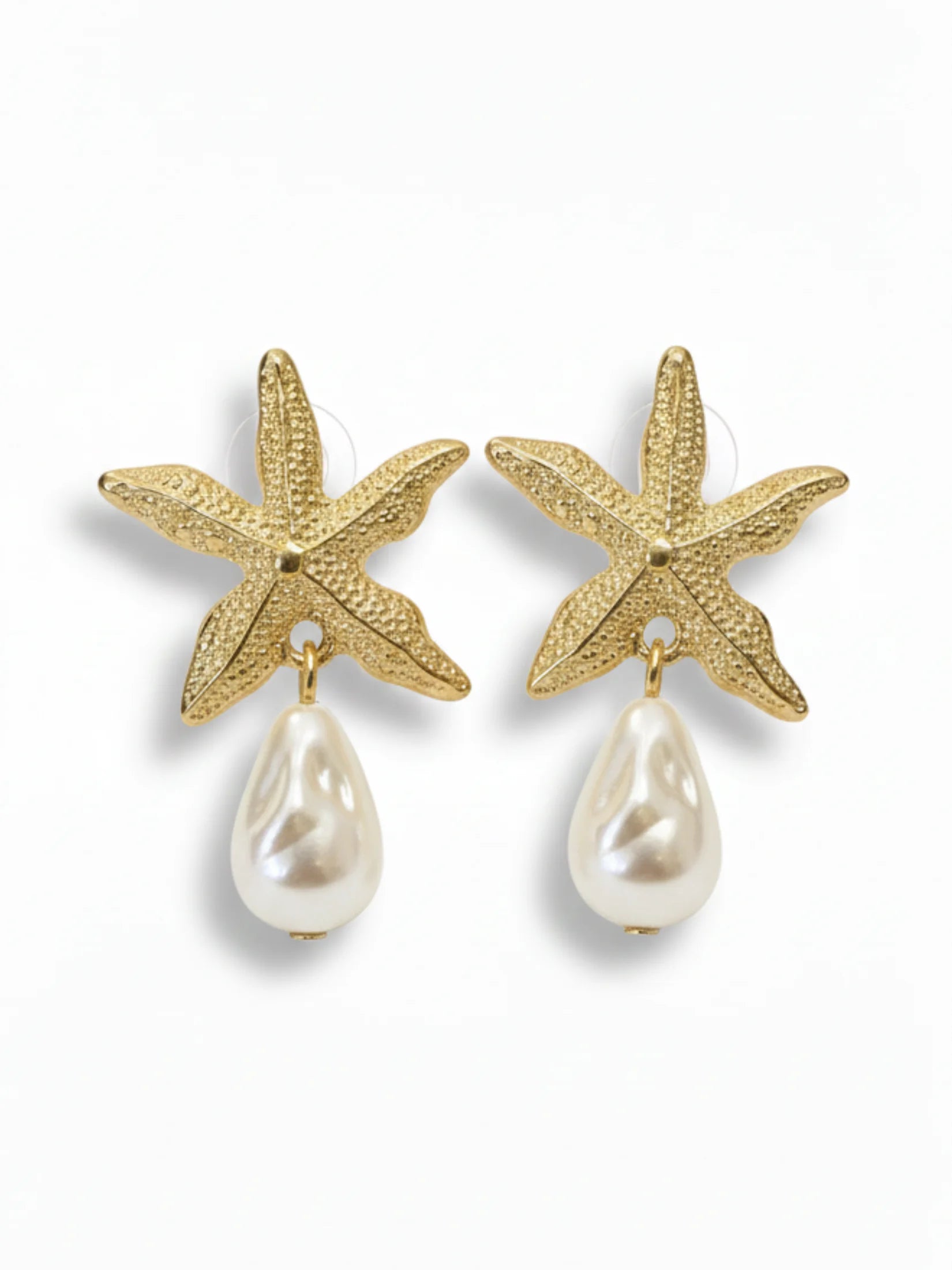 Gold starfish earrings with pearl drops on a white background
