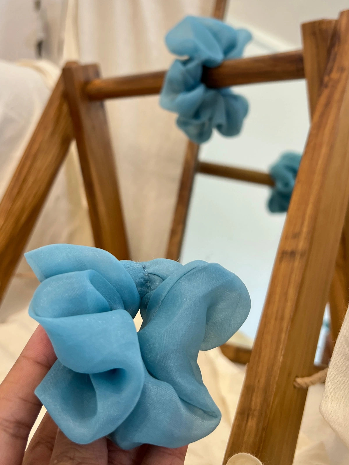 Blue scrunchies on a wooden rack with a blurred background