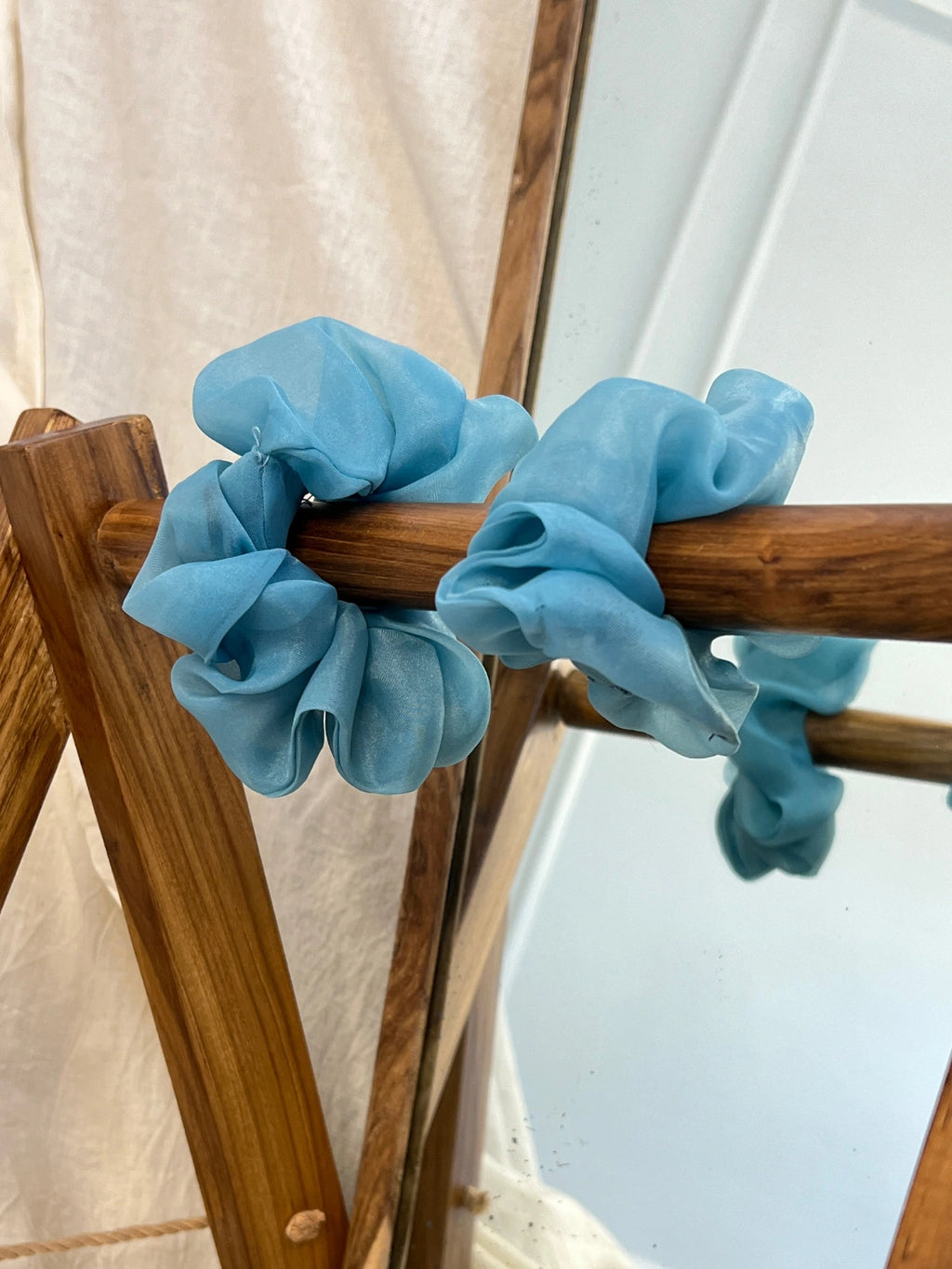 Blue scrunchies on a wooden chair with a white curtain background