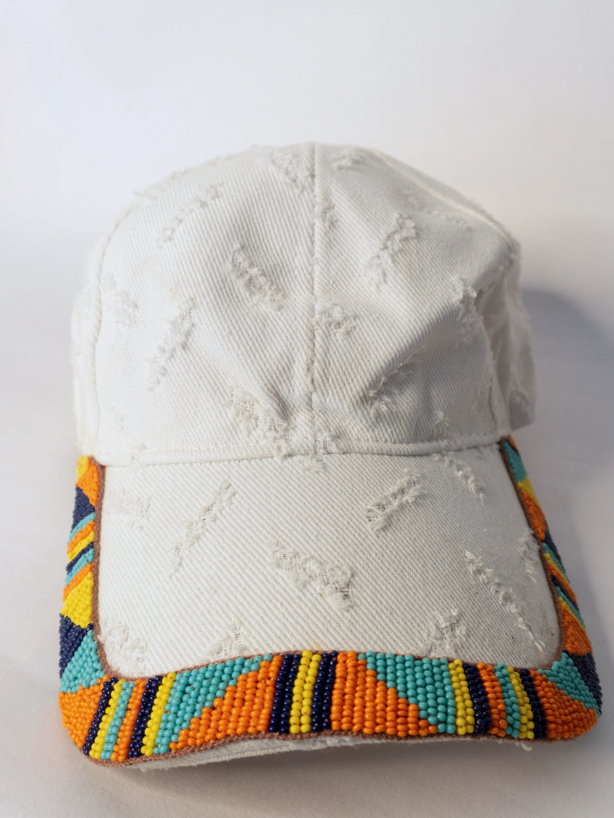 White cap with colorful beaded trim on a white background