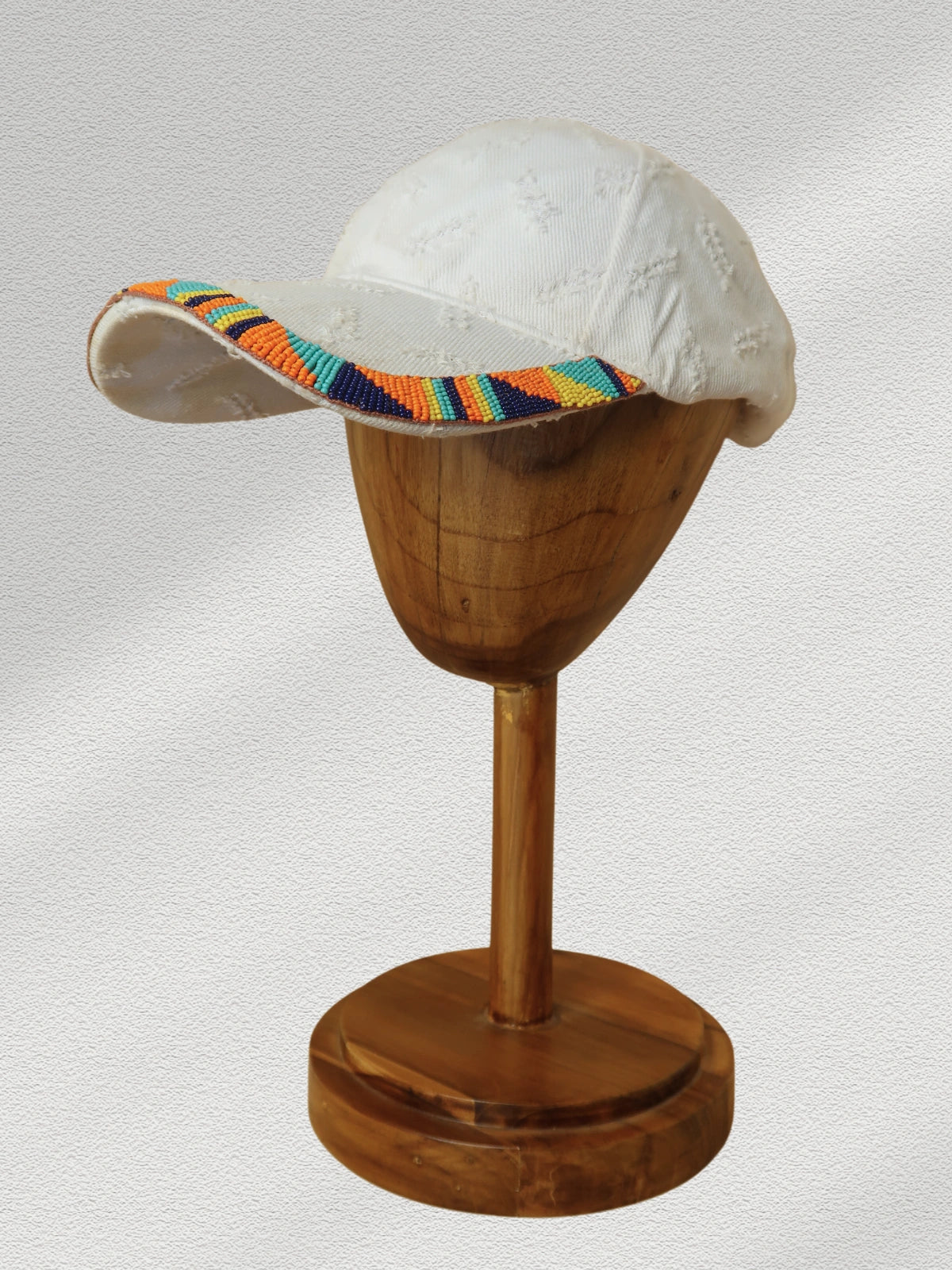White cap with colorful rim on a wooden stand against a gray background