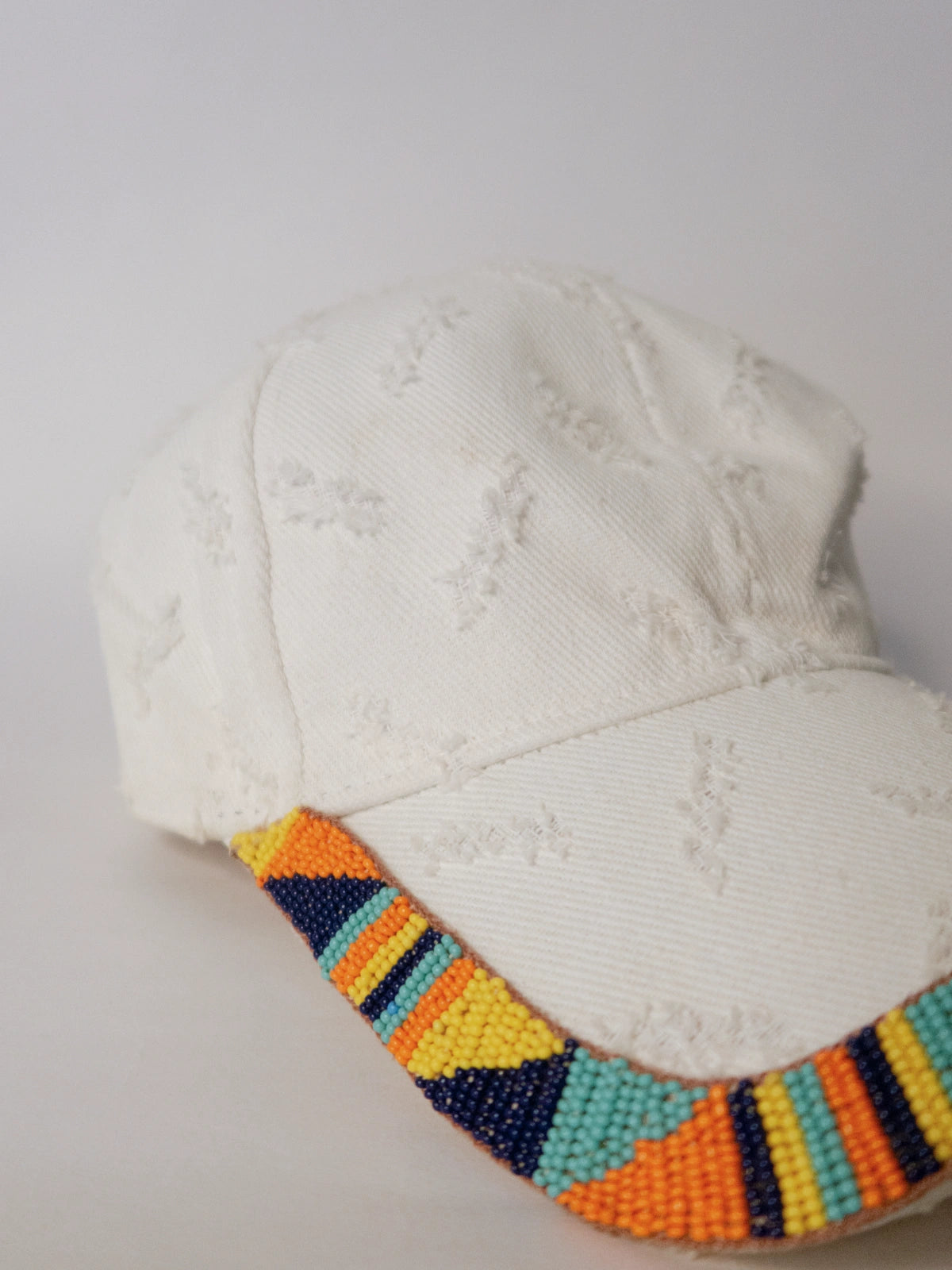 White cap with colorful beaded band on a light gray background