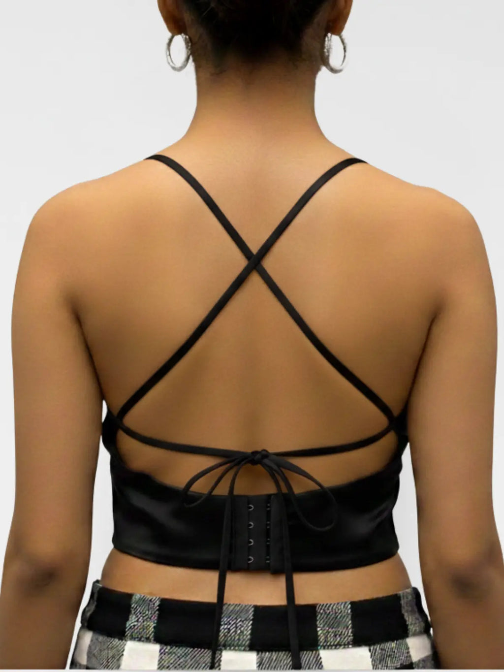 Black strappy top worn by a person on a plain background