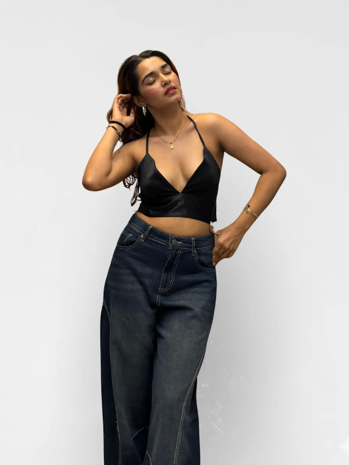 Woman wearing a black top and dark jeans against a white background