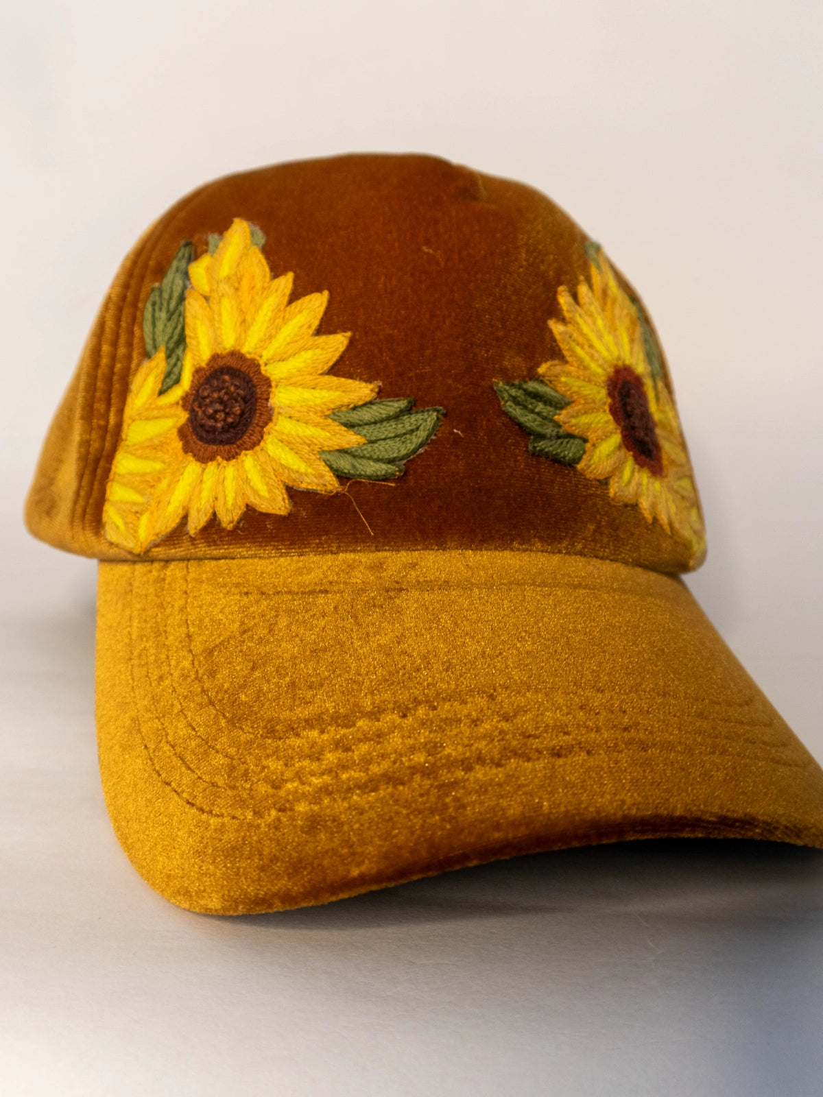 Brown cap with sunflower designs on a white background