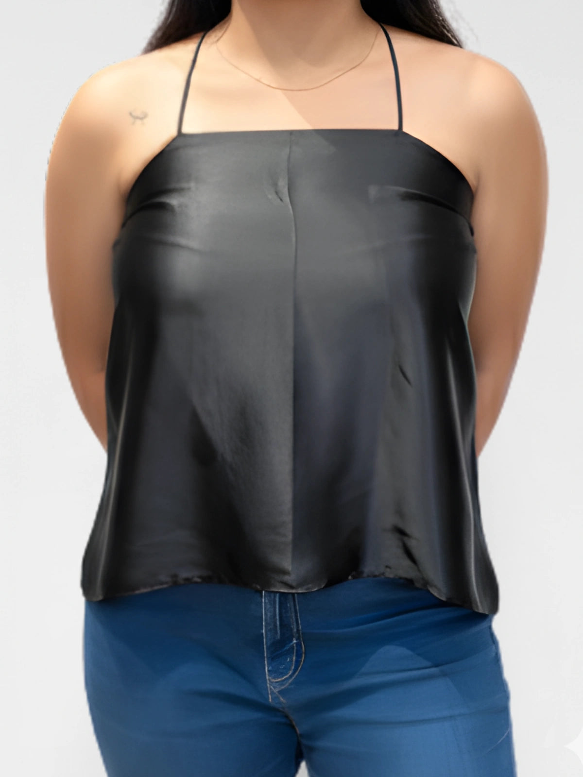 Person wearing a black halter top and blue jeans on a white background
