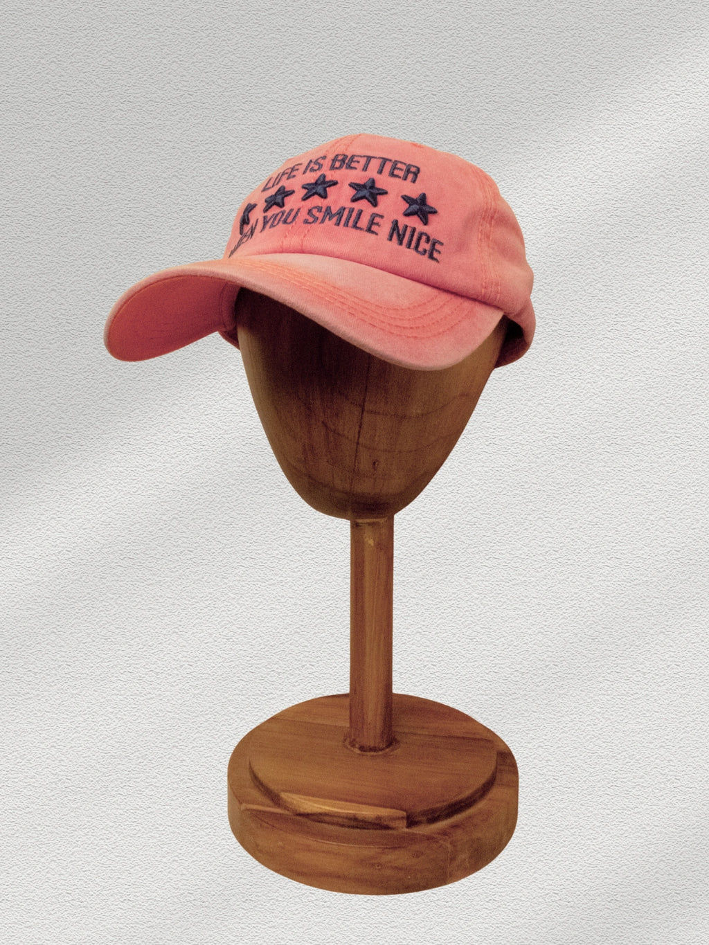 Pink cap on a wooden mannequin head with a white background