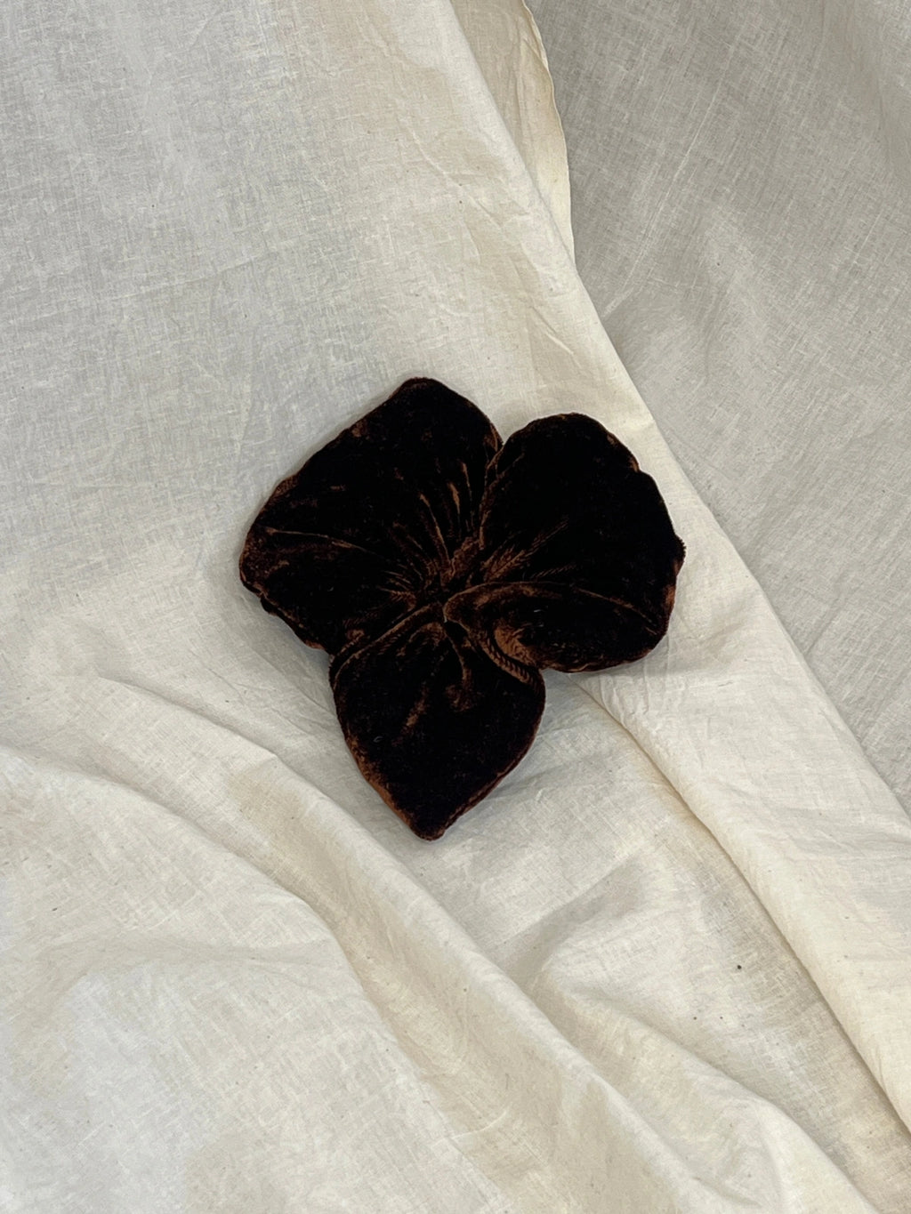 Dark brown flower-shaped object on a white fabric background