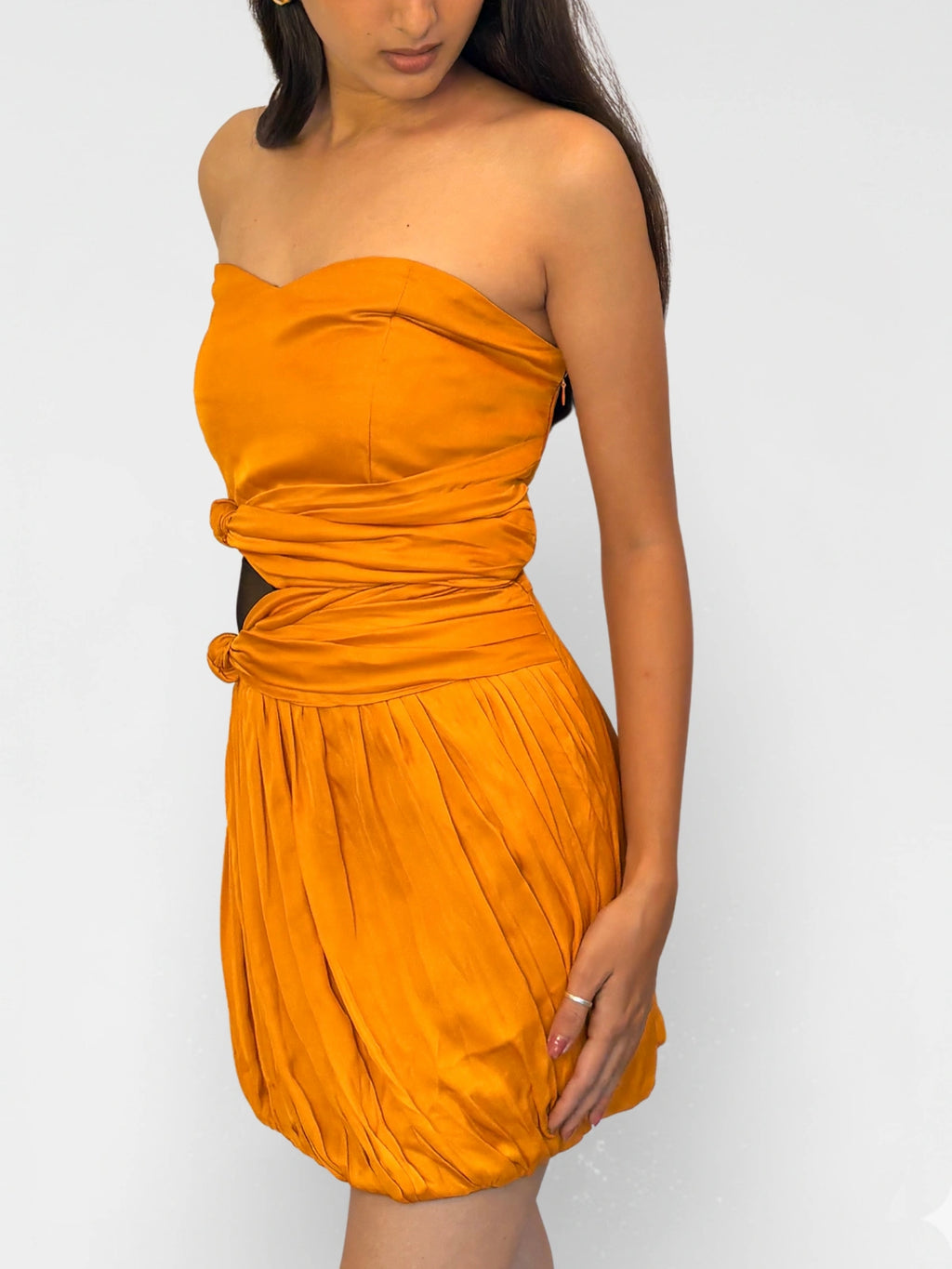 Woman wearing an orange strapless dress against a white background