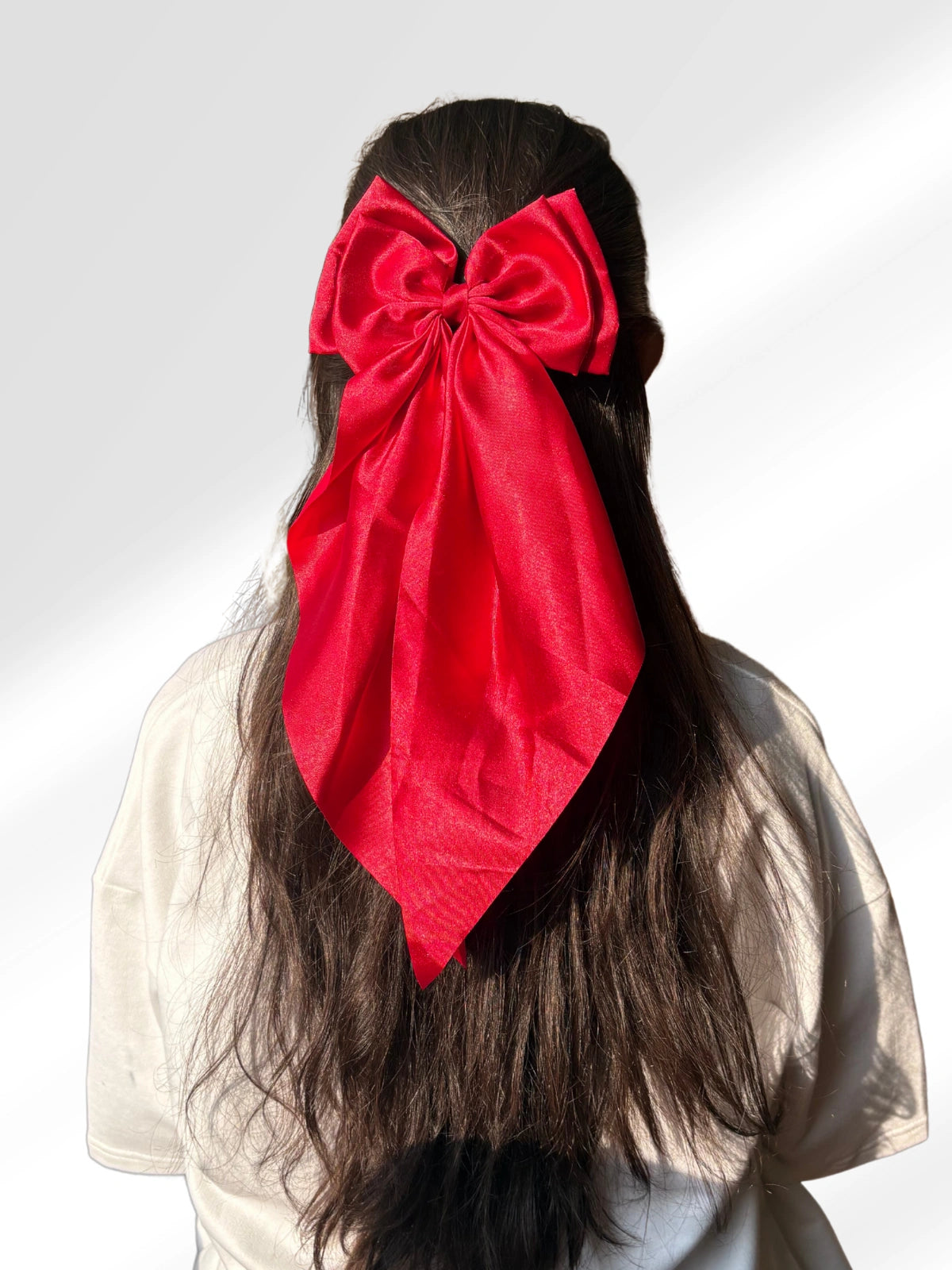 Person with long hair wearing a large red bow on a white background