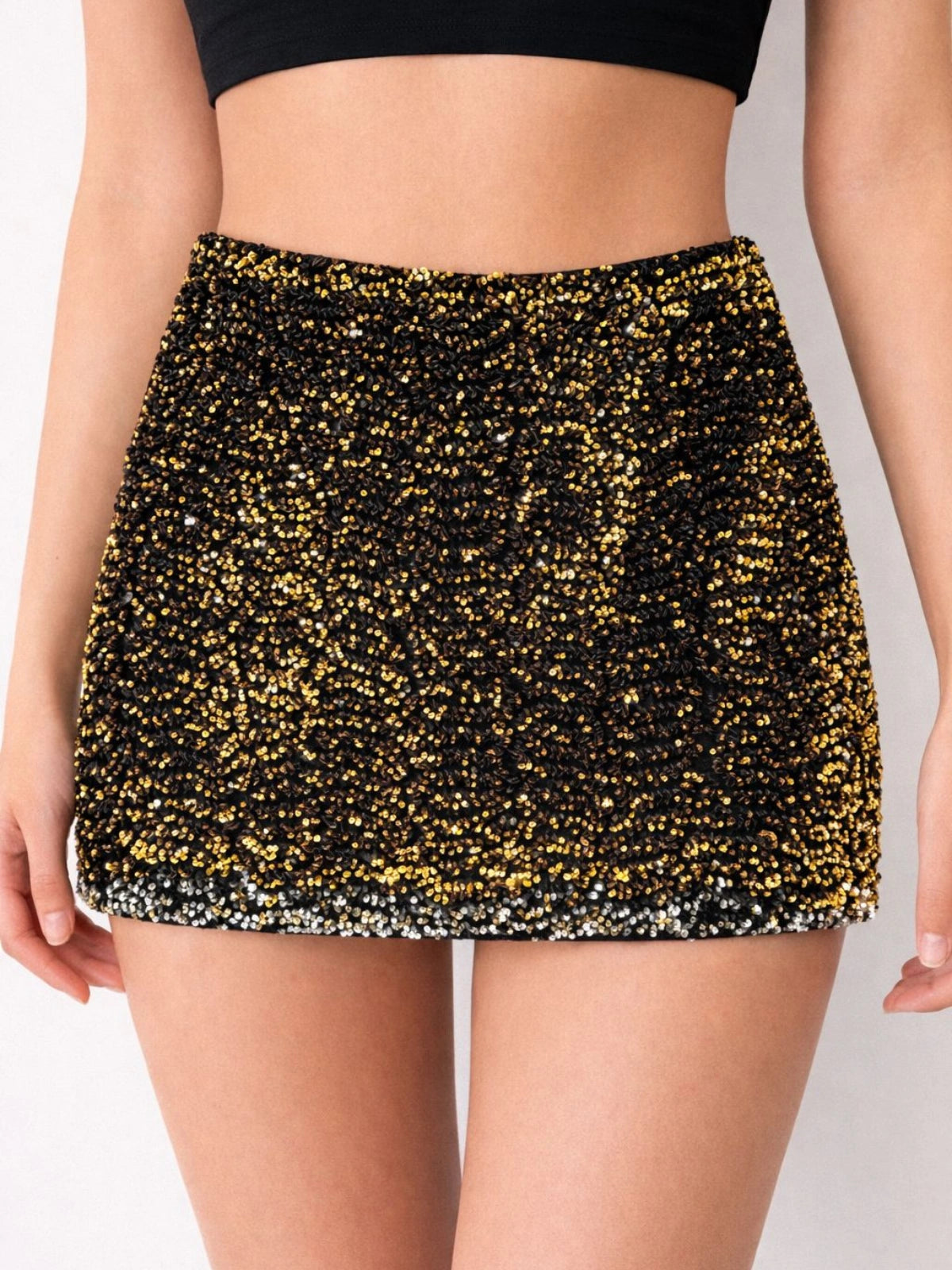 Black and gold sequin skirt worn by a person on a plain background
