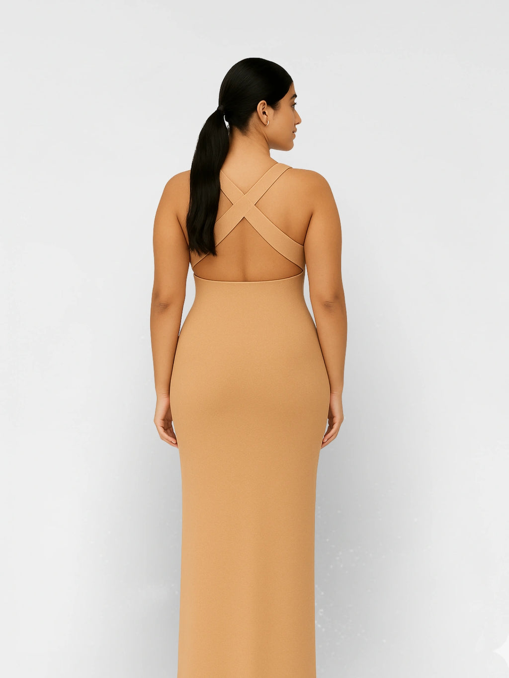 Woman wearing a tan dress with a cut-out back on a white background